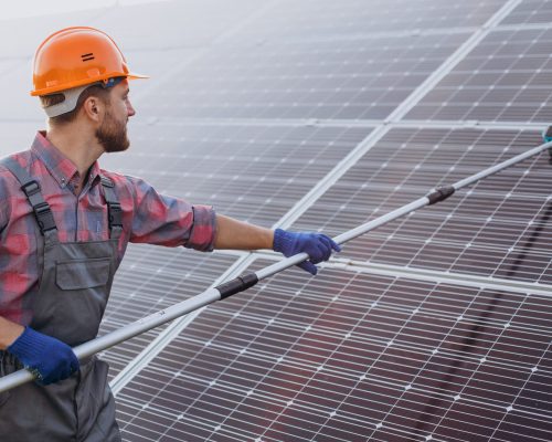 Male worker cleaning solar panels